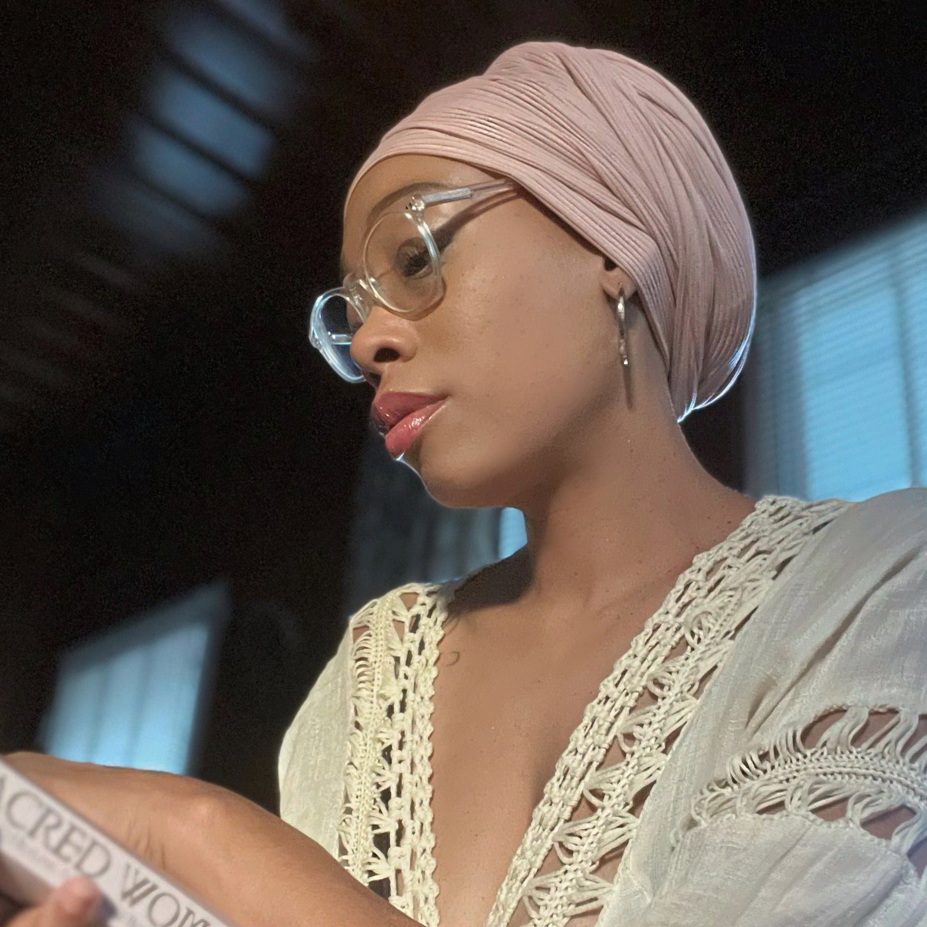 model wearing stretch ribbed rose, light pink head wrap while reading a book