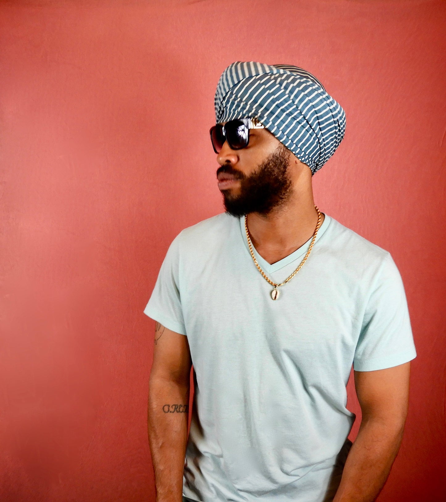 black male with beard wearing a turban style ocean grey and white striped head wrap