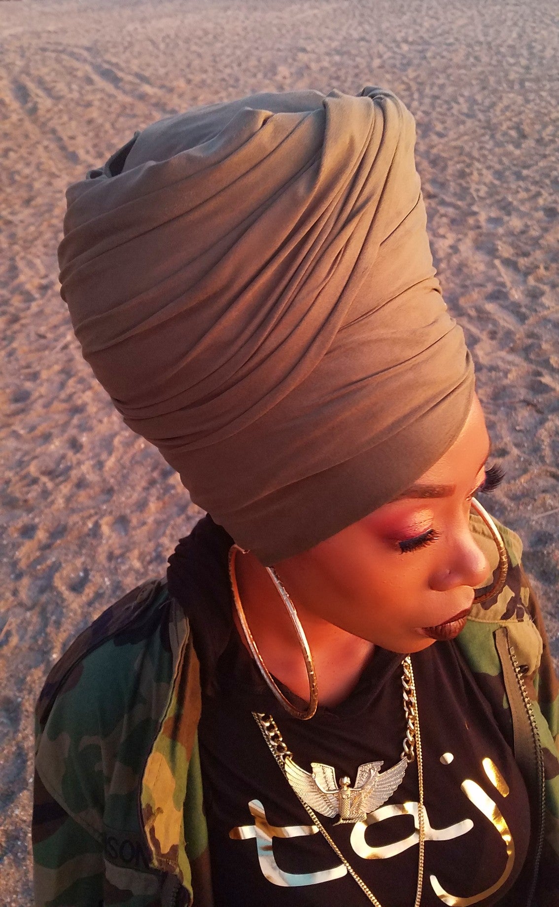 black model walking on beach wearing soft, textured, stretchy, grayish- brown faux suede head wrap